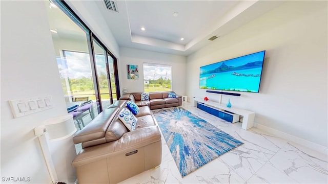 living area with a tray ceiling, marble finish floor, and visible vents