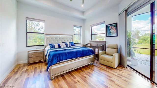 bedroom with light hardwood / wood-style flooring, ceiling fan, multiple windows, and access to outside