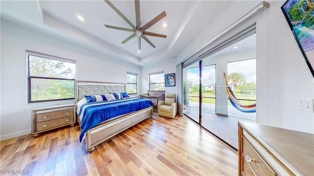 bedroom with a tray ceiling, recessed lighting, light wood-style flooring, access to outside, and baseboards