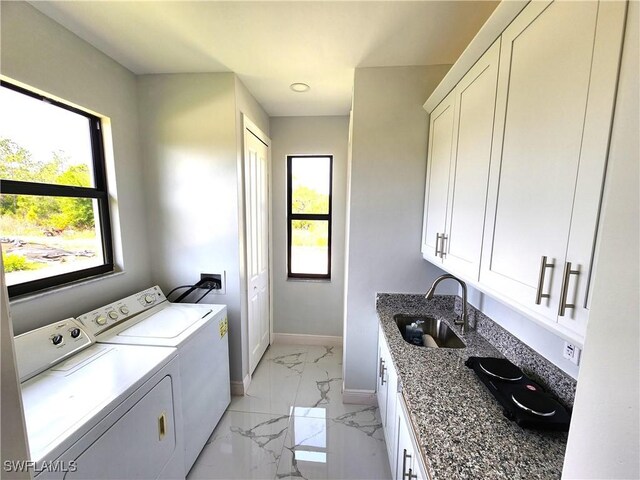 laundry area with light tile patterned floors, washer and dryer, cabinets, and sink