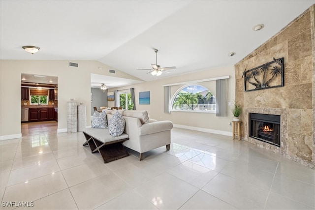 living room featuring lofted ceiling, ceiling fan, a fireplace, and light tile patterned floors