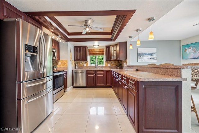 kitchen with decorative backsplash, a tray ceiling, stainless steel appliances, crown molding, and decorative light fixtures