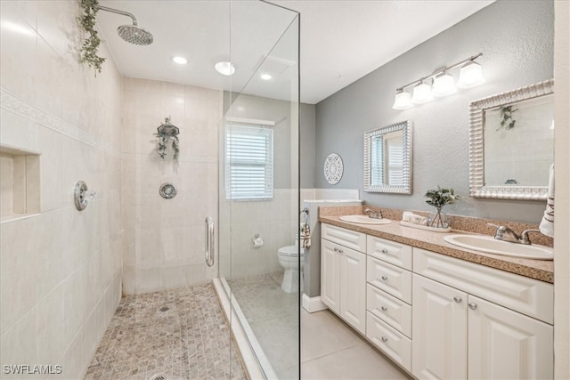 bathroom featuring a shower with door, vanity, toilet, and tile patterned floors