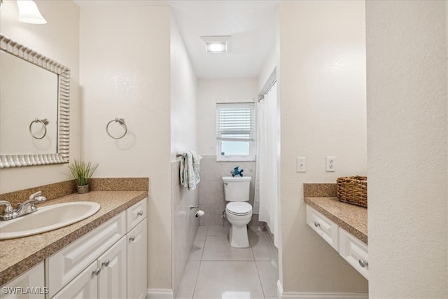 bathroom with tile walls, vanity, toilet, and tile patterned flooring