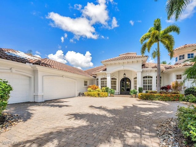 mediterranean / spanish-style house with a garage and french doors