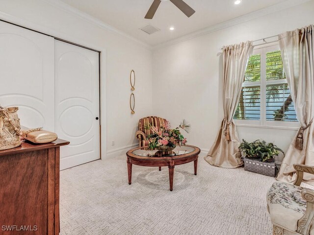 living area with light colored carpet, ceiling fan, and ornamental molding