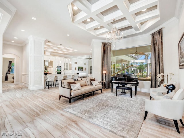 living room featuring beamed ceiling, ceiling fan with notable chandelier, ornamental molding, and coffered ceiling