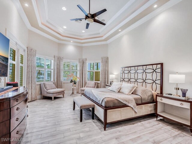 bedroom with ceiling fan, light hardwood / wood-style floors, a towering ceiling, and crown molding