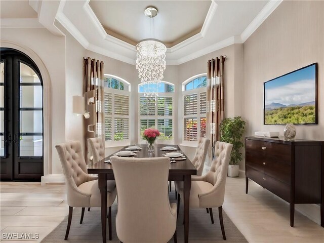 dining area featuring a raised ceiling, crown molding, light hardwood / wood-style flooring, and an inviting chandelier