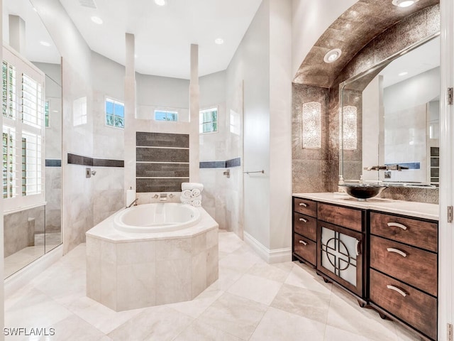 bathroom featuring vanity, independent shower and bath, and a healthy amount of sunlight