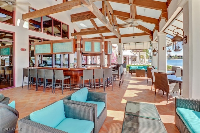 interior space with beamed ceiling, light tile patterned floors, and ceiling fan