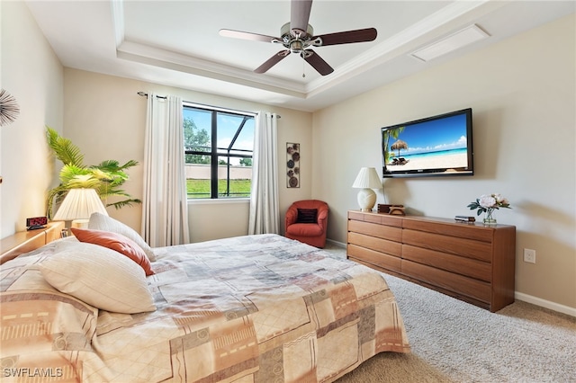 carpeted bedroom with a tray ceiling, ceiling fan, and ornamental molding