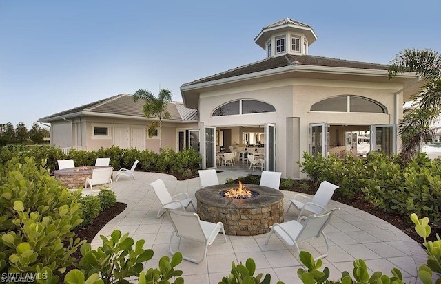 rear view of property featuring a patio area and a fire pit