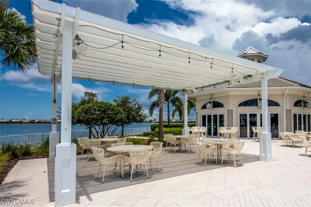 view of patio featuring outdoor dining area, a water view, fence, and a pergola