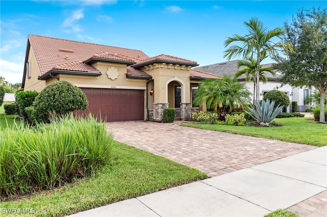 mediterranean / spanish house featuring a garage, decorative driveway, a tile roof, and stucco siding