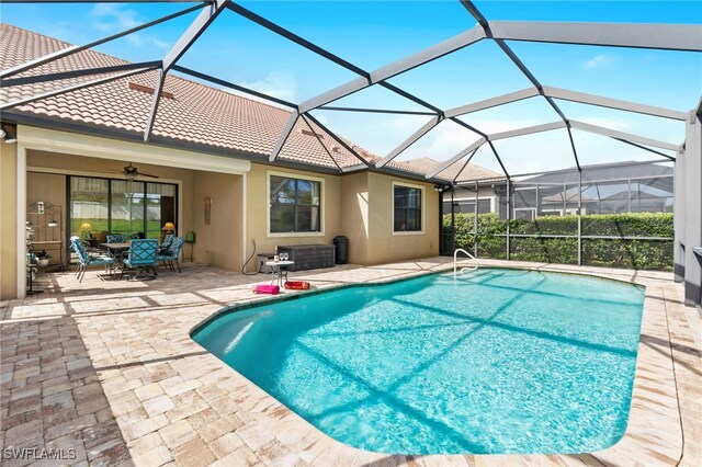 view of swimming pool featuring ceiling fan, a lanai, and a patio