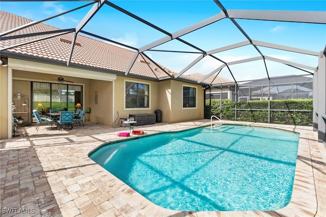 outdoor pool with a ceiling fan, glass enclosure, and a patio area