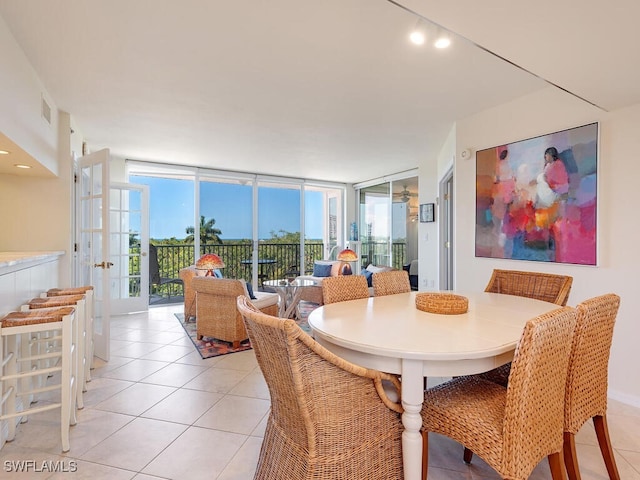 tiled dining area featuring a wall of windows and french doors