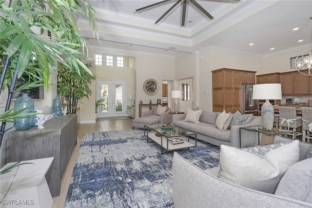 tiled living room with ceiling fan with notable chandelier, crown molding, and a high ceiling