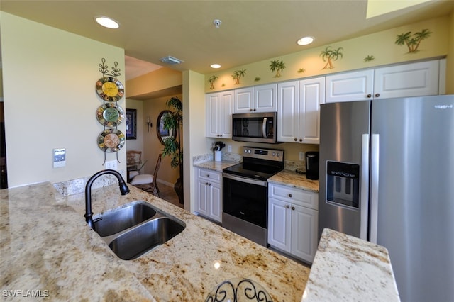 kitchen featuring stainless steel appliances, white cabinets, sink, and light stone countertops