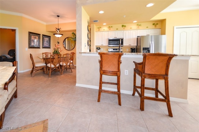 kitchen with a breakfast bar, stainless steel appliances, white cabinetry, and kitchen peninsula