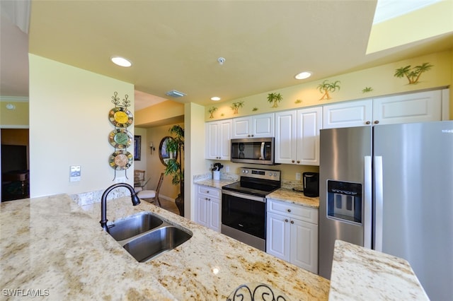 kitchen featuring stainless steel appliances, light stone countertops, and white cabinetry