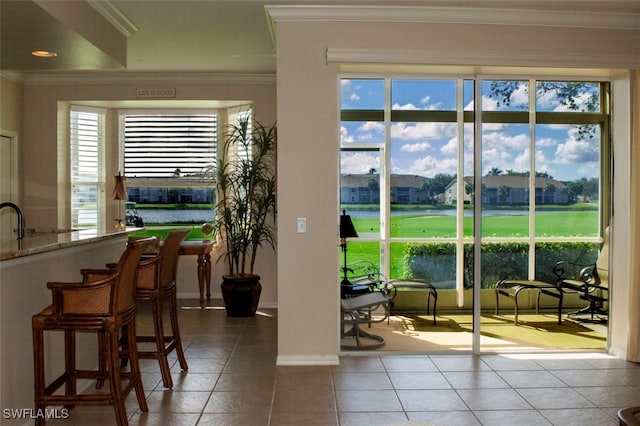 entryway featuring tile patterned flooring, ornamental molding, and a water view