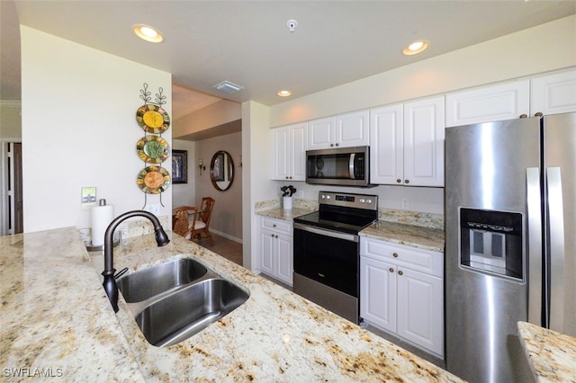 kitchen with white cabinetry, sink, light stone countertops, and appliances with stainless steel finishes