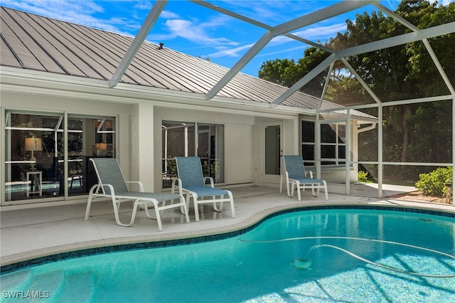 view of pool with glass enclosure and a patio