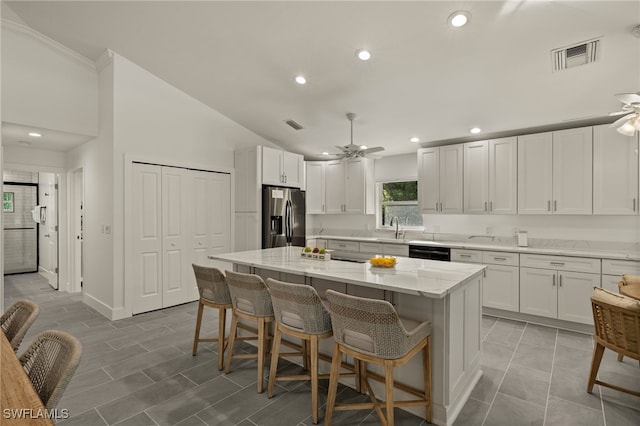 kitchen featuring white cabinetry, a kitchen island, light stone countertops, ceiling fan, and stainless steel fridge with ice dispenser