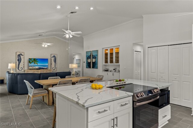 kitchen with a kitchen island, vaulted ceiling, stainless steel electric range, ornamental molding, and ceiling fan