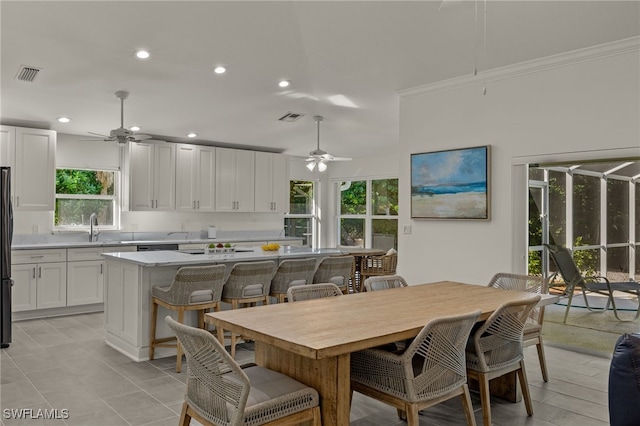 tiled dining room with ceiling fan, sink, and ornamental molding