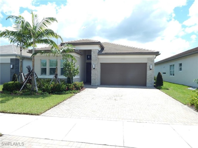 view of front facade with decorative driveway, a tile roof, stucco siding, an attached garage, and a front lawn