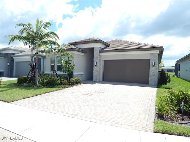 view of front of home with a garage, decorative driveway, a tile roof, and stucco siding