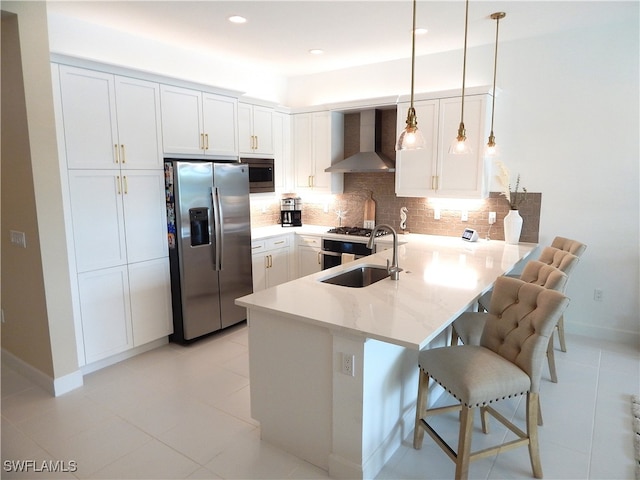 kitchen featuring stainless steel appliances, sink, wall chimney exhaust hood, kitchen peninsula, and a breakfast bar area