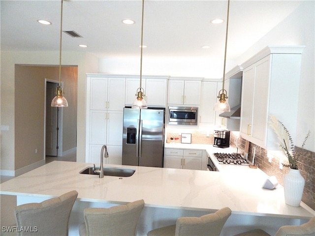 kitchen with a breakfast bar area, stainless steel appliances, sink, and decorative light fixtures