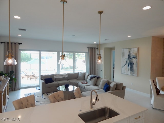 kitchen featuring a healthy amount of sunlight, sink, decorative light fixtures, and a kitchen island with sink