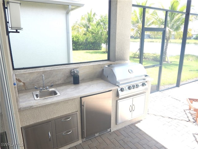 interior space with a water view, sink, an outdoor kitchen, and grilling area