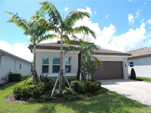 view of front of home with a tiled roof, decorative driveway, an attached garage, and stucco siding