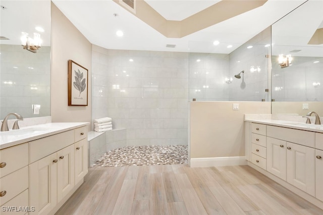 bathroom with vanity, tile walls, hardwood / wood-style flooring, and a tile shower