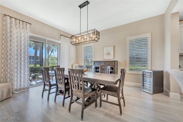 dining area with beverage cooler, a chandelier, and light hardwood / wood-style floors