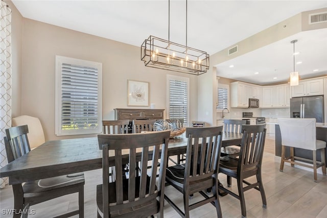 dining space with a notable chandelier, sink, and light hardwood / wood-style floors