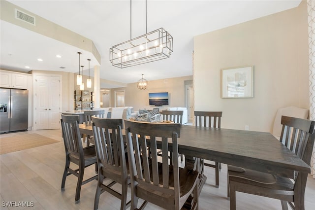 dining area featuring light hardwood / wood-style flooring and a notable chandelier