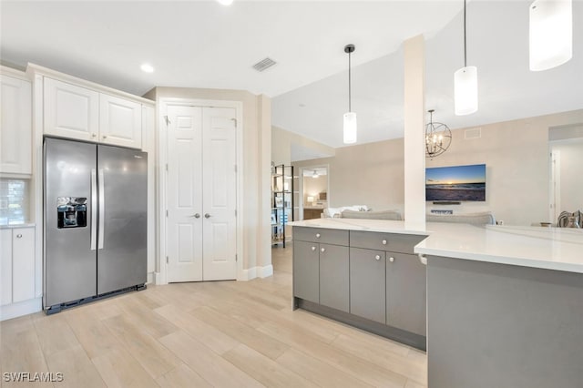 kitchen featuring gray cabinetry, decorative light fixtures, light hardwood / wood-style floors, white cabinetry, and stainless steel fridge