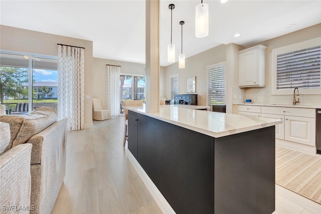 kitchen with white cabinets, hanging light fixtures, plenty of natural light, and sink