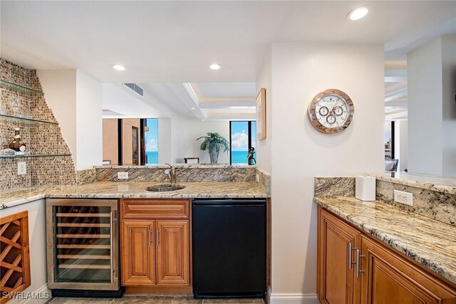 bar with backsplash, dishwasher, light stone counters, sink, and beverage cooler