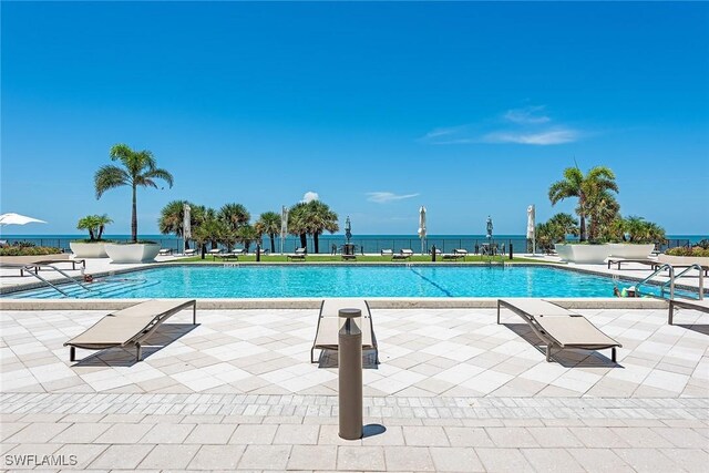 view of swimming pool featuring a water view and a patio