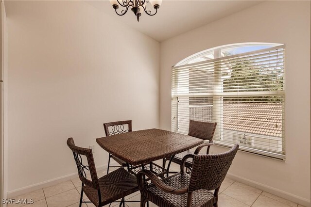 tiled dining room with lofted ceiling and a chandelier