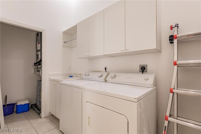 clothes washing area featuring sink, cabinets, washer and dryer, and light tile patterned flooring