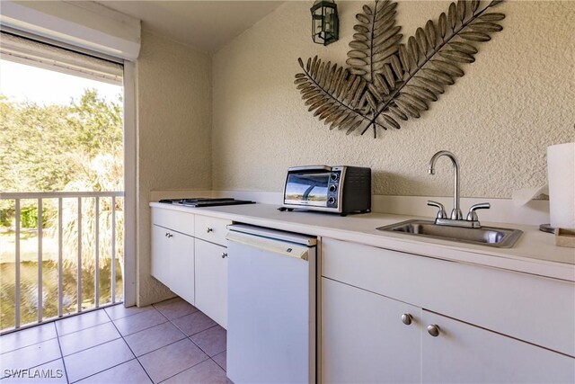 kitchen featuring light tile patterned flooring, dishwasher, white cabinetry, and sink